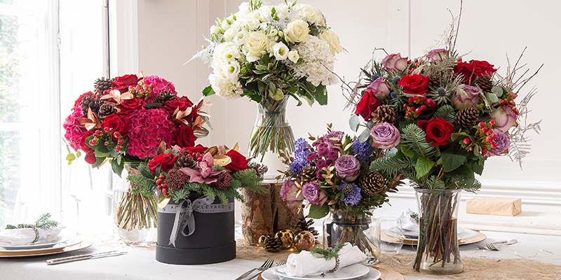Five Christmas bouquets arranged on a table.