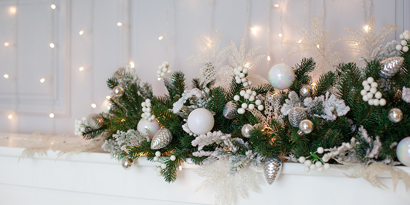 A floral Christmas garland with white decorations and pine foliage. 