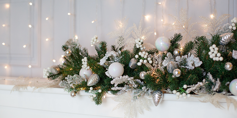 A floral Christmas garland with white decorations and pine foliage.