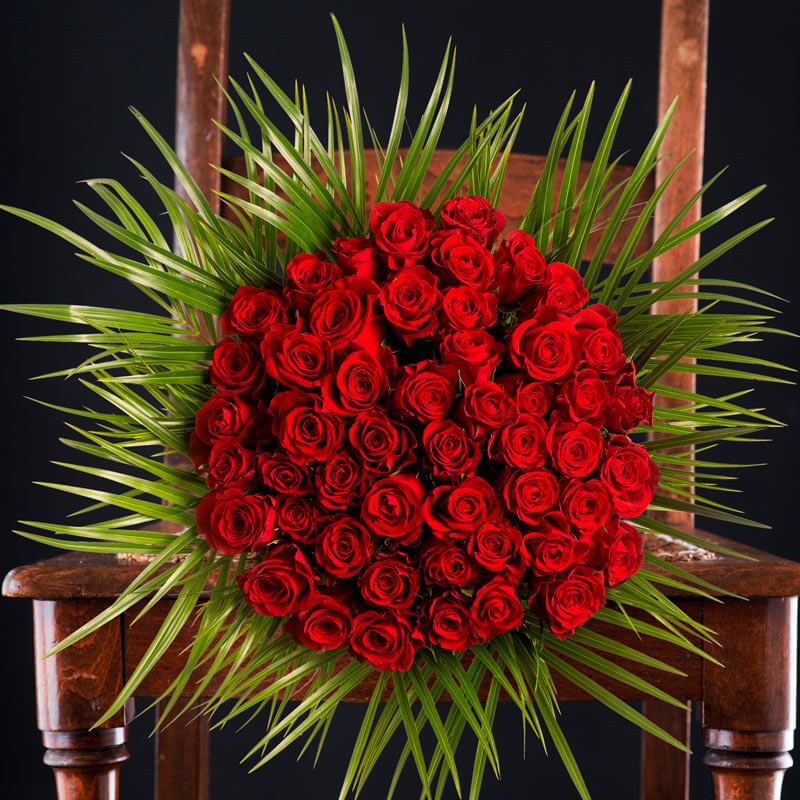 A bouquet of 50 red roses with palm foliage